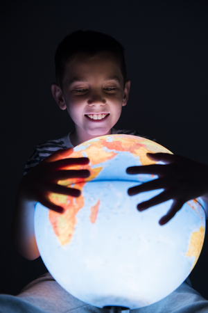 boy holding globe in the darkの写真素材