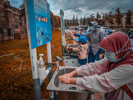malang, indonesia -14 february, 2021 : a Muslim woman and her two children washing their hands in...