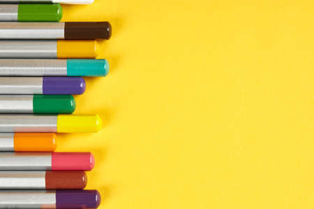 colored pencil on bright yellow background. view from above. left border. pencils with grey body and colored tips. vibrant colorsの写真素材