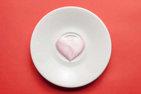 pink heart symbol on a white dinner plate. view from above. romance and valentine day concept