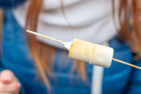 girl eats hot marshmallow outdoors at christmas festiveの写真素材