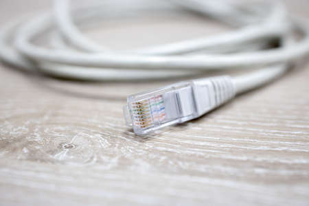 lan and internet rj45 cable connector at light wooden table background. selective focusの写真素材