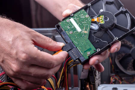 person holds dusty hdd from desktop for cleaning or upgrade old broken hardware. hard drive sata and...
