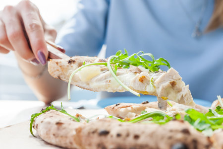 Girl holding pizza slice. pizza with cheese, pineapple, chicken and vegetablesの写真素材