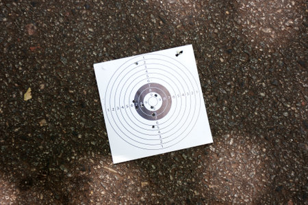 used paper target with bullet holes at urban asphalt background. procrastination and attack conceptの写真素材