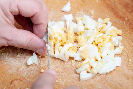 sliced boiled chicken eggs on the kitchen board. preparation of the ingredient for the dish....