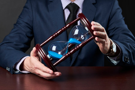 businessman holds hourglasses at his hands. business time conceptの写真素材