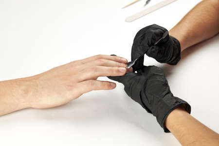 manicurist during work using nail metal stick. a man manicure process. an unrecognizable caucasian...