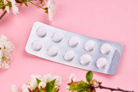medicine blister pills over pink background with decorated spring flowersの写真素材