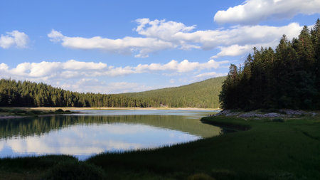 A large body of water that is completely surrounded by trees and rocksの写真素材