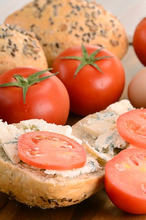 Breadboard with blue cheese, rolls and tomatoesの写真素材