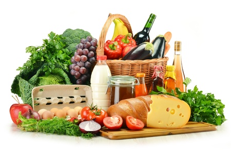 Groceries in wicker basket including vegetables, fruits, bakery and dairy products and wine isolated on whiteの写真素材