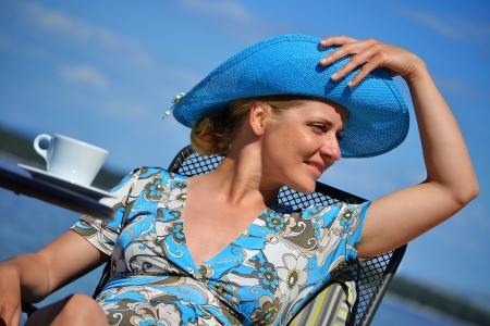 Young woman with the blue hat having coffee on the beachの写真素材