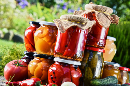 Jars of pickled vegetables and fruits in the garden. Marinated food.の写真素材