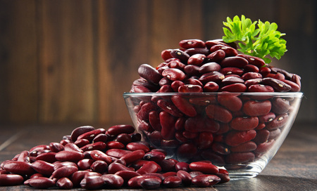 Composition with bowl of kidney bean on wooden table.