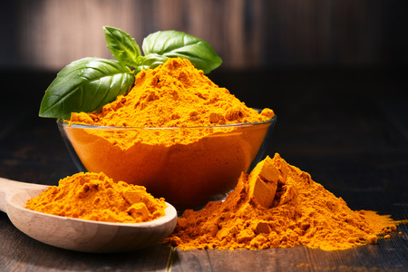 Composition with bowl of turmeric powder on wooden table.の写真素材