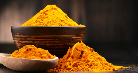 Composition with bowl of turmeric powder on wooden table.の写真素材