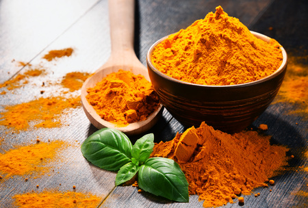 Composition with bowl of turmeric powder on wooden table.の写真素材