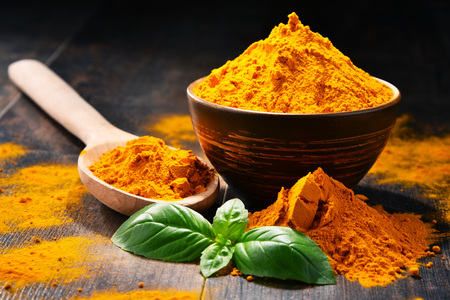 Composition with bowl of turmeric powder on wooden table.の写真素材