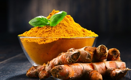 Composition with bowl of turmeric powder on wooden table.の写真素材