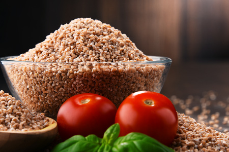 Bowl of uncooked spelt on wooden table.の写真素材