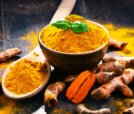 Composition with bowl of turmeric powder on wooden table.の写真素材