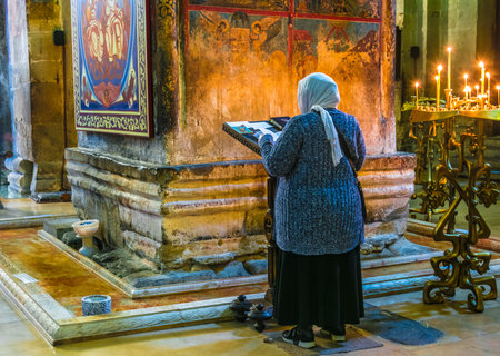 MTSKHETA, GEORGIA - OCT 25, 2018: Woman praying in Svetitskhoveli Cathedral in the historic town of Mtskheta, Georgiaのeditorial素材