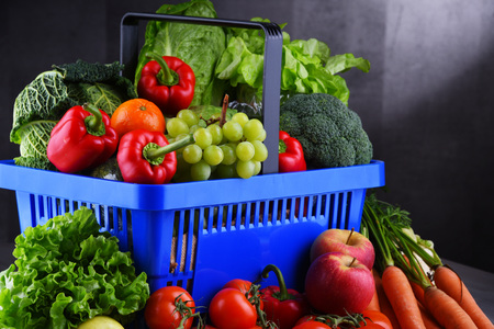 Fresh organic fruits and vegetables in plastic shopping basket.の写真素材