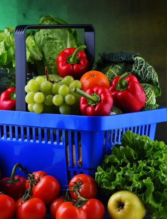 Fresh organic fruits and vegetables in plastic shopping basket.の写真素材