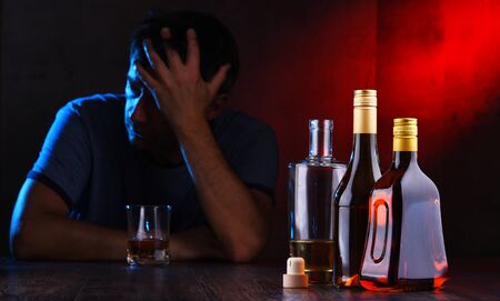 Bottles with alcoholic beverages and the figure of a drunk manの写真素材