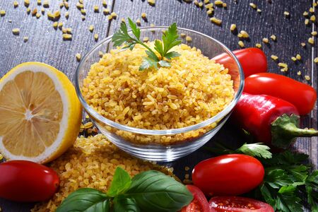 Bowl of uncooked bulgur on wooden table.の写真素材