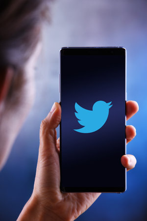 POZNAN, POL - JUL 10, 2019: Woman holding smartphone displaying logo of Twitter, an American online microblogging and social networking serviceのeditorial素材