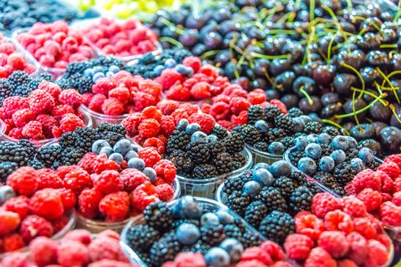 Raspberries, blueberries and blackbarries sold on the street market stall.の写真素材