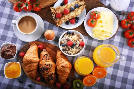 Breakfast served with coffee, orange juice, croissants, pancake, egg, cereals and fruits.の写真素材