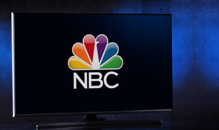 Foto de POZNAN, POL - FEB 04, 2020: Flat-screen TV set displaying logo of NBC, an American English-language commercial terrestrial radio and television network that is a flagship property of NBCUniversal - Imagen libre de derechos