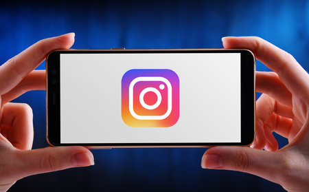 POZNAN, POL - MAY 21, 2020: Hands holding smartphone displaying logo of Instagram, a photo and video-sharing social networking service owned by Facebookのeditorial素材