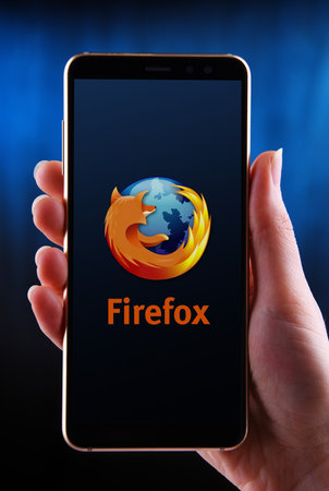 POZNAN, POL - MAY 21, 2020: Hands holding smartphone displaying logo of Firefox, a free and...