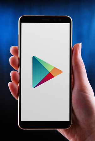 POZNAN, POL - MAY 21, 2020: Hands holding smartphone displaying logo of Google Play, an American...