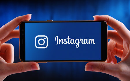POZNAN, POL - MAY 21, 2020: Hands holding smartphone displaying logo of Instagram, a photo and video-sharing social networking service owned by Facebookのeditorial素材