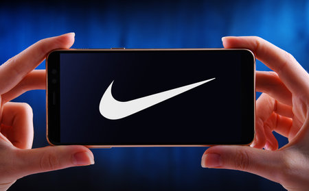 POZNAN, POL - JUN 12, 2020: Hands holding smartphone displaying logo of Nike, an American multinational corporation producing footwear, apparel, equipment and accessoriesのeditorial素材