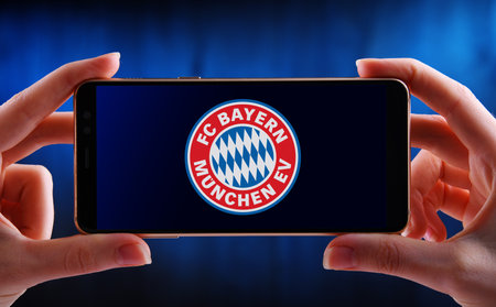POZNAN, POL - JUN 20, 2020: Hands holding smartphone displaying logo of FC Bayern, is a German professional sports club based in Munich, Bavariaのeditorial素材