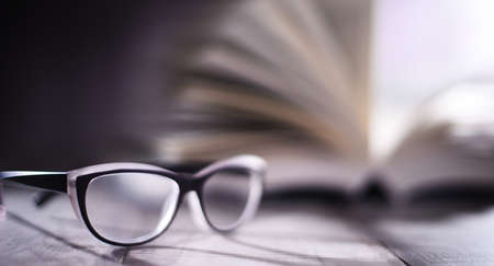 Composition with glasses and open book on the table.