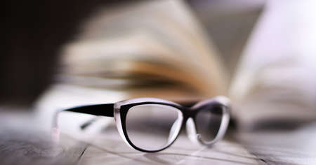Composition with glasses and open book on the table.