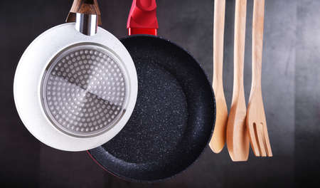 Two hanging frying pans and kitchen utensilsの写真素材