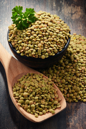 Composition with bowl of lentils on wooden table.