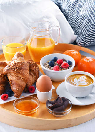 A tray with breakfast on a bed in a hotel room.の写真素材