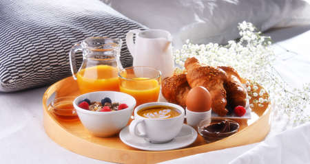 A tray with breakfast on a bed in a hotel room.