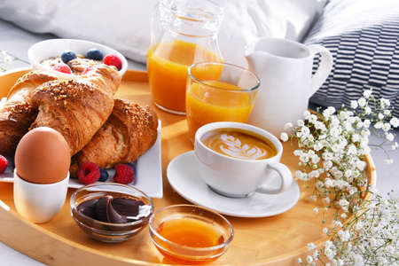 A tray with breakfast on a bed in a hotel room.の写真素材