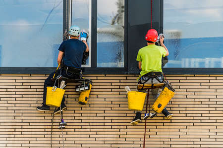Two men cleaning windows on an office buildingの写真素材