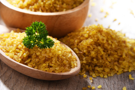 Composition with a bowl and spoon of uncooked bulgur on a table.の写真素材